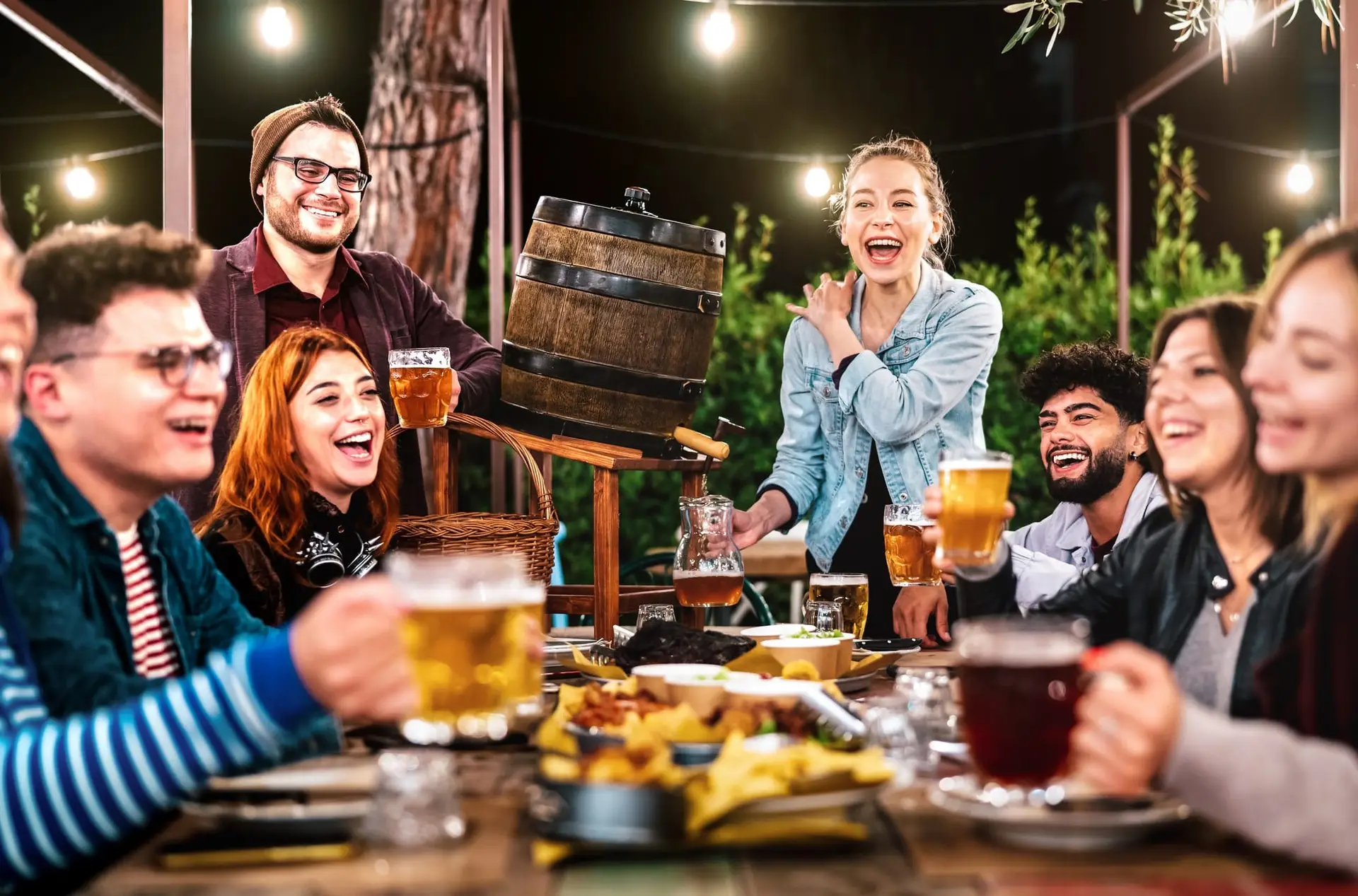 A group of happy men and women having fun at a beer garden in Spain, enjoying good company, drinks, and the expat lifestyle with peace of mind from 247 Expat Insurance.