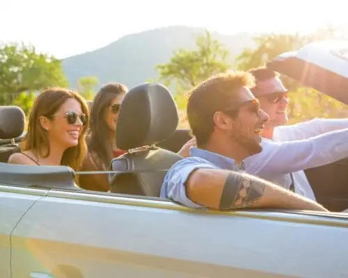 Four adult friends driving on rural road in convertible, Majorca, Spain