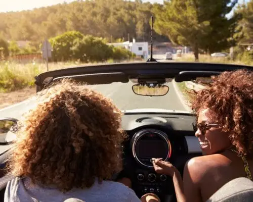 Happy young couple driving in an open top car, Ibiza, Spain